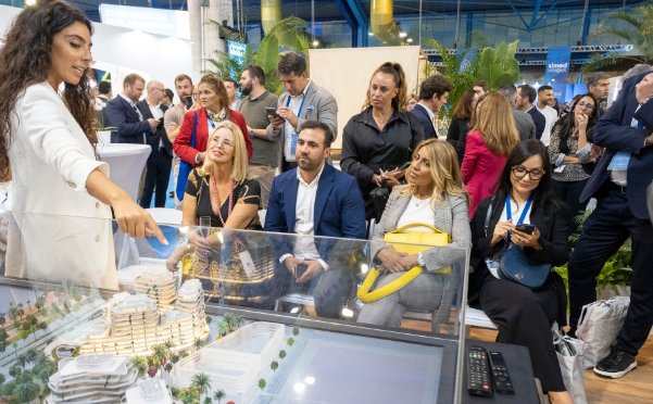 Una comercial muestra una maqueta de una promoción de AEDAS Homes en el SIMed 2024